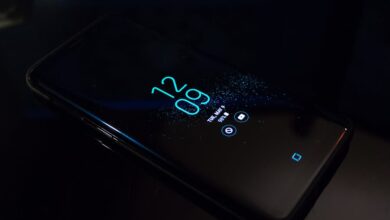 Close-up of a smartphone in the dark displaying digital clock and notifications.
