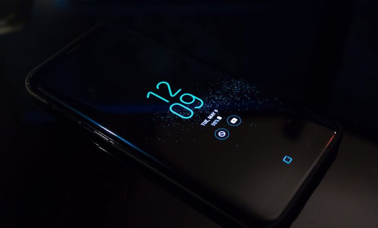 Close-up of a smartphone in the dark displaying digital clock and notifications.