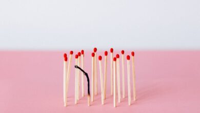 Artistic representation of burnout with matchsticks on a pink surface in a studio setting.
