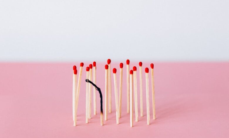 Artistic representation of burnout with matchsticks on a pink surface in a studio setting.