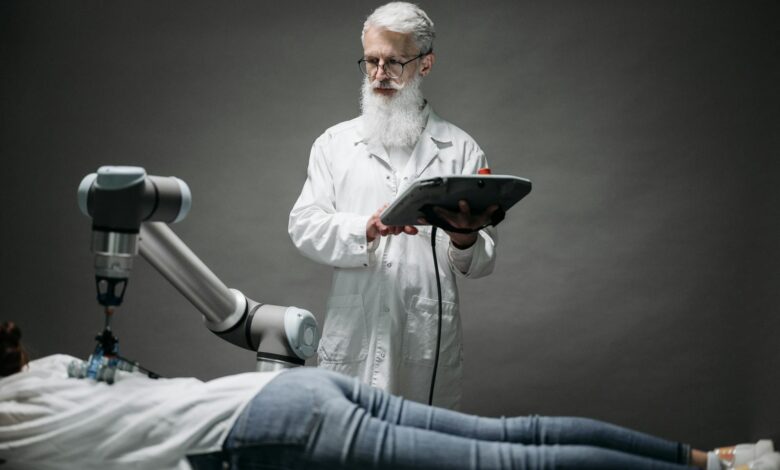 A scientist controls a robotic arm conducting research on a person lying down.