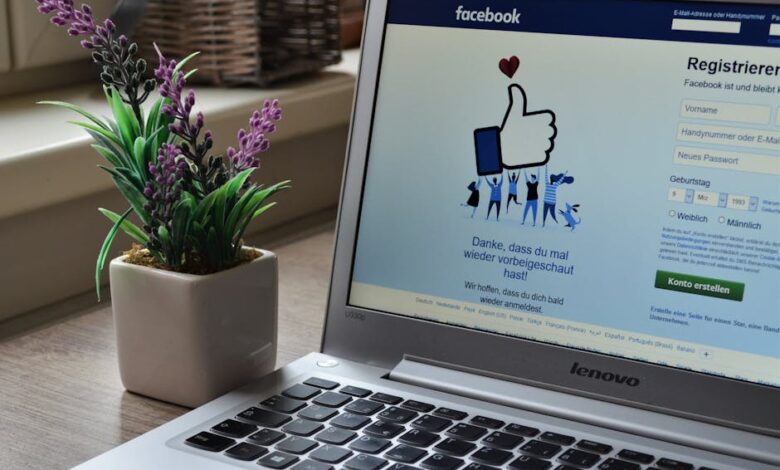 A Lenovo laptop displaying Facebook login beside a lavender plant indoors.
